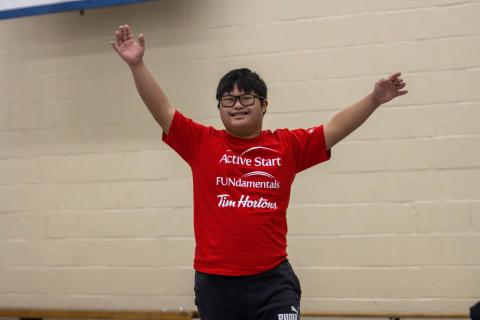 Youth participant raising hands and smiling